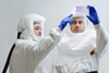 Two scientists in protective clothing examine vials of fluid