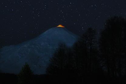 a light on top of a dark mountain