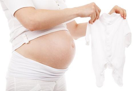 Pregnant_woman_holds_white_babygrow_sleeper