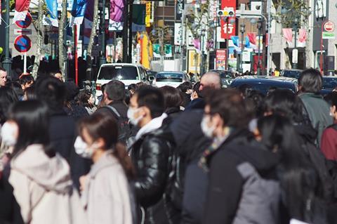 Crowd of people in street wearing protective masks